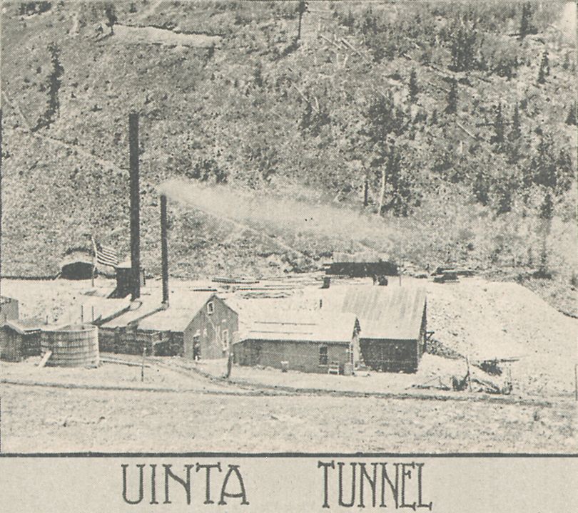    This view is of the surface structures of the Uinta Tunnel in Eclipse Gulch going into the northwest slope of Battle Mountain. The adit portal is scene just beyond the American Flag near left side. While the quality of this view is not so great, is still gives info about how the area was, and more importantly, some of the structures that appeared at this Adit type of a mine.
   There are three large structures, a shed and at least one water tank. One of the large structures is a power house and probably a compressor plant – with a horse driven off-loading of coal on the side towards the photographer. No railroad ever came to this spot so this was a horse wagon type operation to get ore out, material supplies in, down the valley at right, I believe, as that leads down to a M.T. spur.