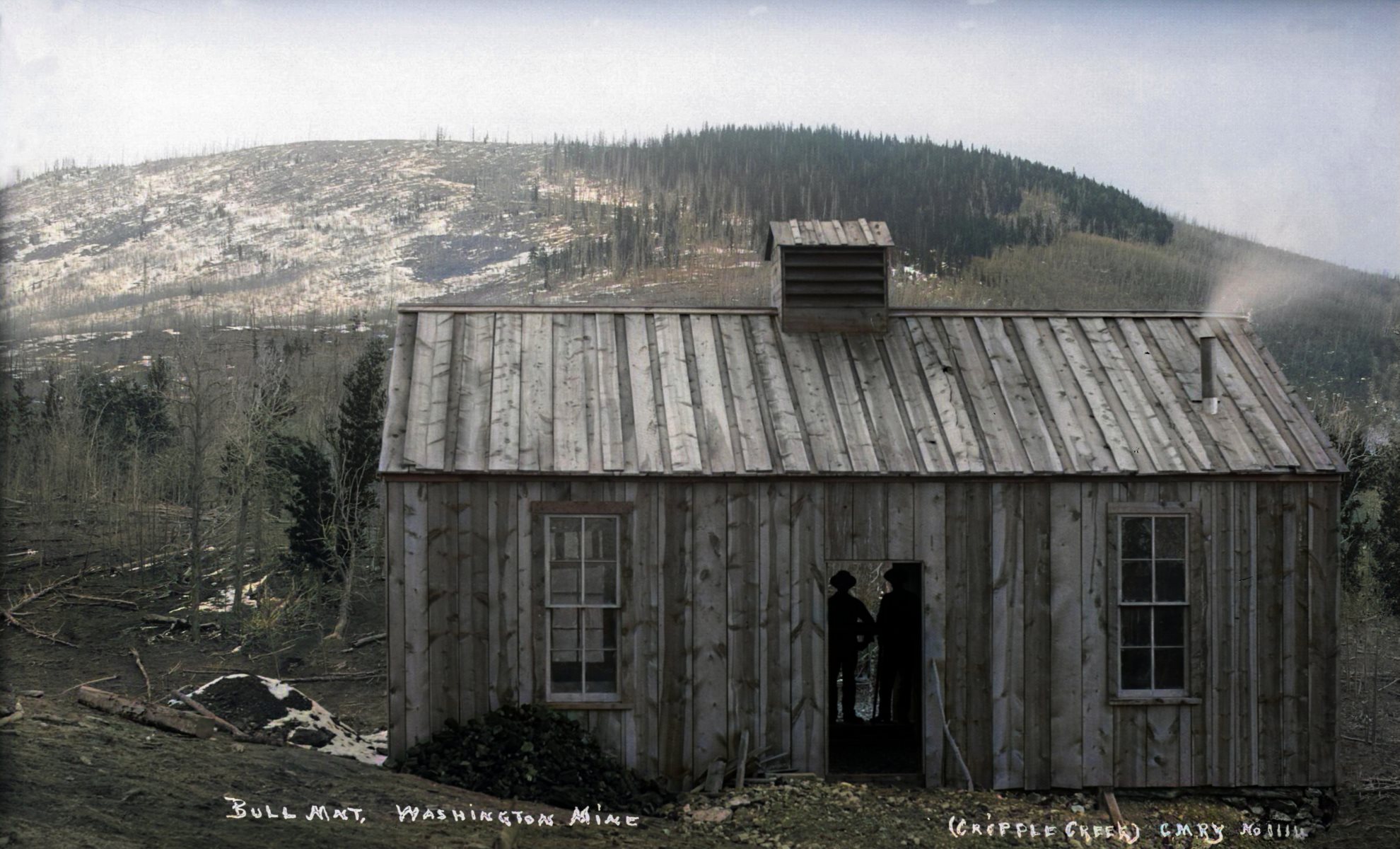 This is the only known photo type of the Washington Mine as per today (October 1, 2021) that I know about. Found on the Denver Public Library site (Call Number: X-62461). I just worked over the image to create this view. Photo is of a vertical board cabin with two double-hung windows and a doorway, said to be on Bull Mountain, but Battle Mountain it should be, as it shows the early Washington mine. Silhouettes of two men can be seen inside the cabin.
   I did procure the colored version of this image. Source was grayish, or in common speech black & white. Used an online service and tweaked and worked with image to get what looks best to my eyes at the moment.