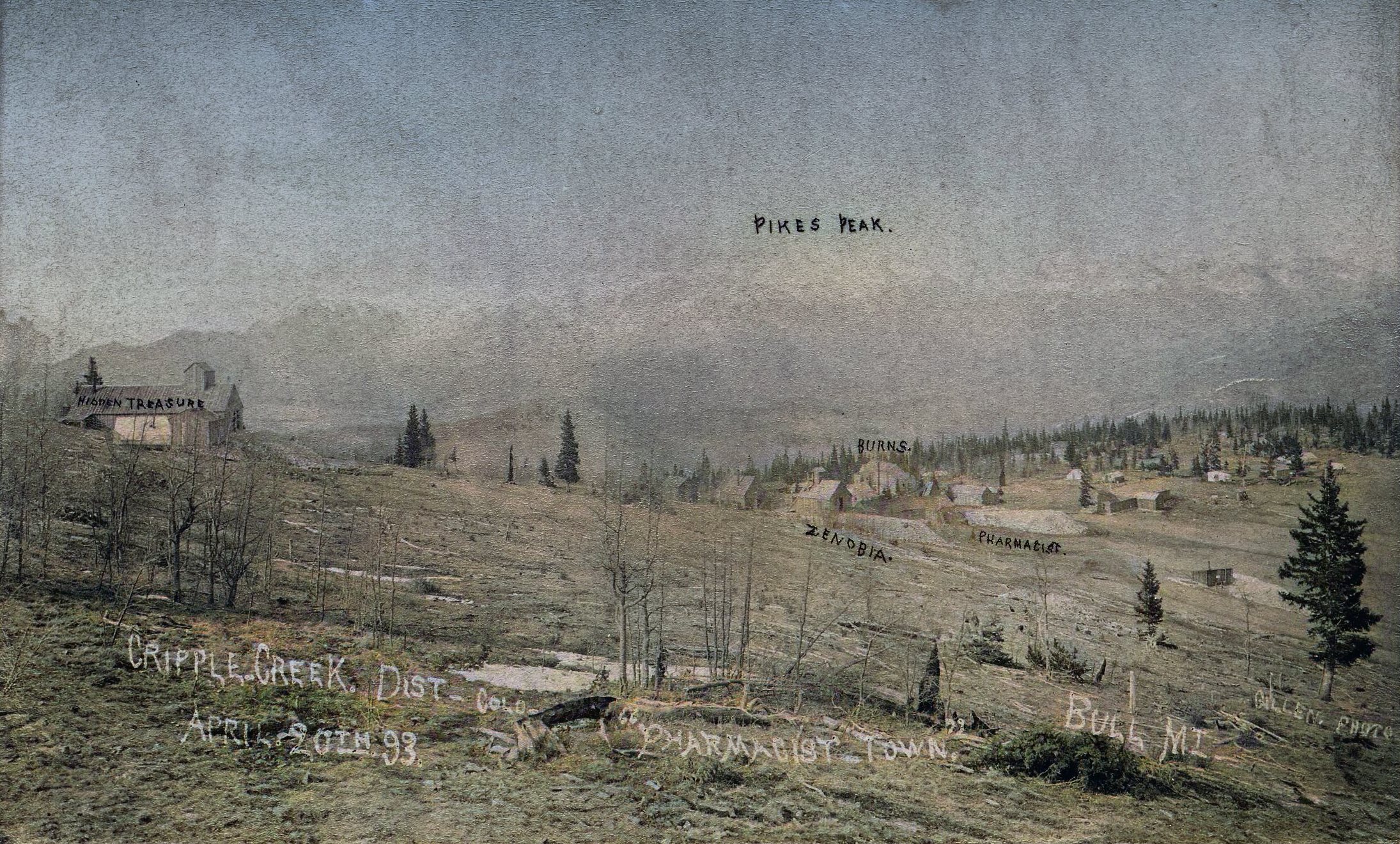 Quite a nice very early view of east side of Bull Hill with some of its mines and the early start of the town of Altman, here called 'Pharmacist Town,' while Bull Hill is called Bull Mountain. Taken April 20, 1893 it feels like a treasure to have, flaws and all!
   Near left-hand side the early Shaft house of the Hidden Treasure Mine is seen, while further downhill, the Zenobia, Pharmacist and Burns Shaft houses are marked out, thankfully. There are more mines, but they are not marked out. 
   I did procure the colored version of this image. Source was grayish, or in common speech black & white. Used an online service and tweaked and worked with image to get what looks best to my eyes at the moment. Source had flaws, somewhat faded, ridges on the photo itself, and it was impossible to bring forward the Pikes Peak Range, but in the end, I worked over it as best as I could.