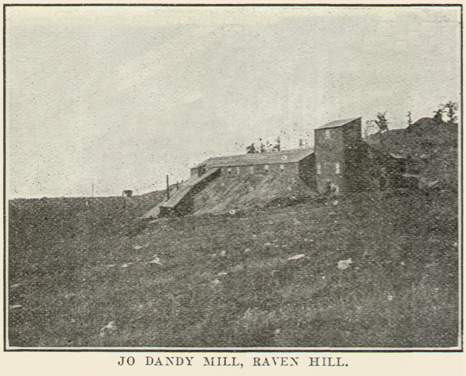 This sadly not so great view of the Kavanaugh-Jo Dandy Mill on Raven Hill shows a plant that is treating a large mine-dump on Raven hill and is right at its source of supply of ore.
   The ore is shoveled and trammed by hand from the dump to the mill, where it is dumped over a grizzly into a 10 by 20-in. Blake crusher set to break to about 1½ inches. Two stands of 16 by 36-in. rolls take the product of the crusher. The product of the rolls is elevated to a hexagonal trommel screen 8 ft. long and set with 1 ft. inclination in the 8 ft. This screen is 3-mesh No. 12 wire and runs at 15 r.p.m. Oversize from this screen returns to the rolls again; and the undersize is delivered to a belt-conveyor which transfers the material to the leaching vats.
   There are four of these leaching vats, 5 ft. deep and 30 ft. in diameter, and of about 125-ton capacity, in use. In charging the material into the vats, considerable care must be exercised to avoid channeling later on account of the large range in size of the material treated. Solution is first applied from below for the same reason. But one strength of solution is used, from 1½ to 2 Ib. per ton. The first solution stands on the ore for 12 hours and is then withdrawn and the ore allowed to drain for aeration. The cyanide leaching treatment is continued for about three days, the vats being allowed to drain well between applications of solution to promote oxidation as thoroughly as time permits, the complete cycle for one charge being about seven days. Just enough water wash is used at the last to keep up the solution in the mill; and then the exhausted ore is shoveled out of the vat by contract and trammed in hand-pushed cars to the dump.
   This would seem to be one of few mills in the district not troubled by a lack of convenient dumping room.
   The pregnant solutions are precipitated by zinc shavings in the usual 6-compartment boxes, the barren solution going to the storage vats. The cyanide solutions are made up to strength by adding the salt at the head of the zinc-boxes to keep the precipitation good.
   Thomas Kavanaugh, who is operating both this and the Homestake plants, says the rock is a sylvanite ore containing considerable arsenic and manganese and is extremely refractory, with not over 10% of free gold. He says he is securing about an 85% extraction and that the ore runs about $2 grade, which is an extremely good result on such coarse refractory material.