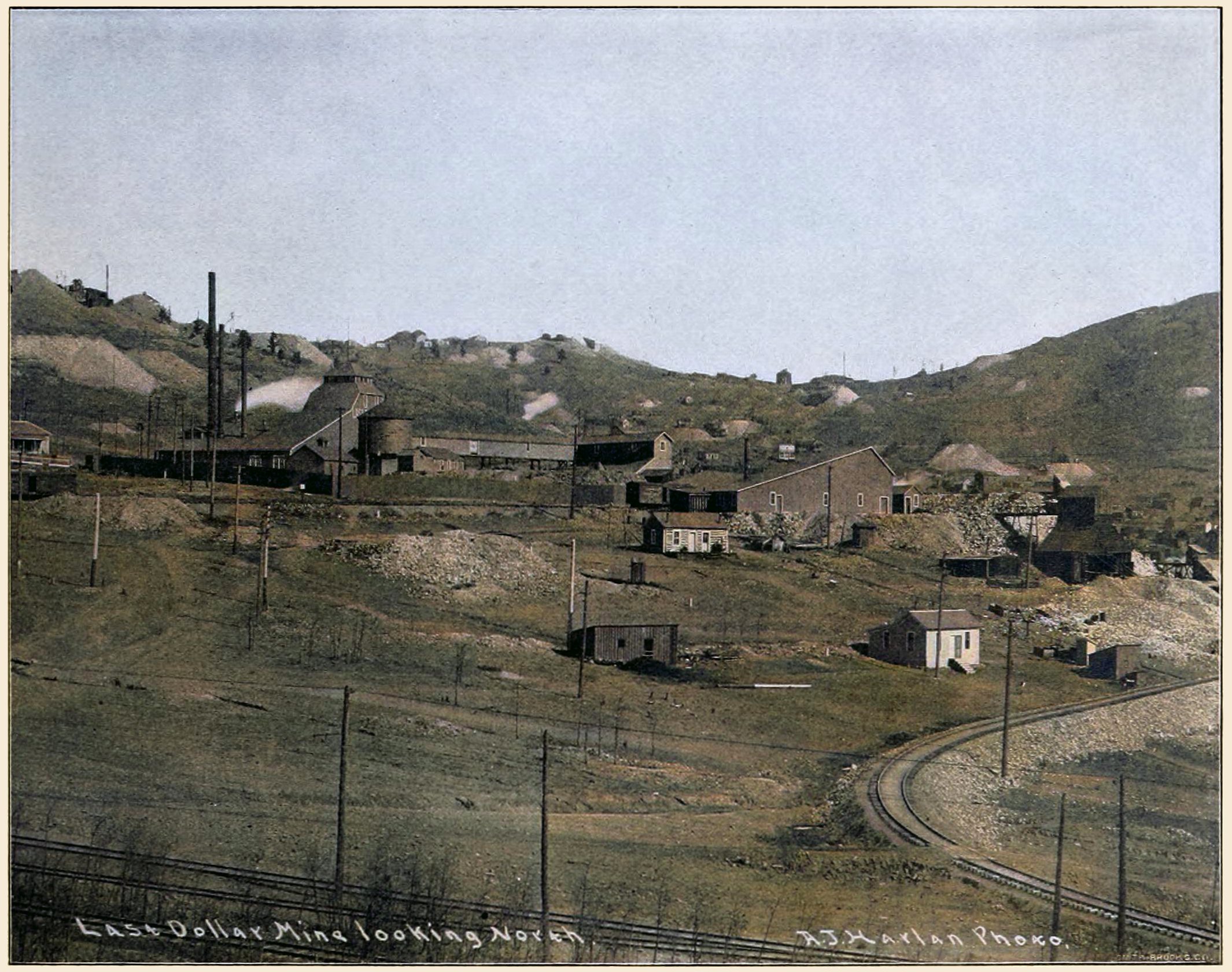 While it is marked with Last Dollar looking North, it also shows part of the Short Line branch track towards Portland/Ajax mine, before it became part of the new High Line that went around of Goldfield, and the original High Line trolley line runs in the foreground showing part of a junction and spur track leading into Dyer Station, outside the view at left.
   Also, in the extreme foreground, the 3-ft narrow gauge track of a sidetrack of the Golden Circle can been seen, going towards what would later become the Portland Mill location. Then, about middle of photo, there stands a F. & C.C. boxcar up on the track passing by the Last Dollar mine.
   In addition, there are quite a few structures around providing good modeling inspiration! I did procure the colored image used; source had a gray-tone image.