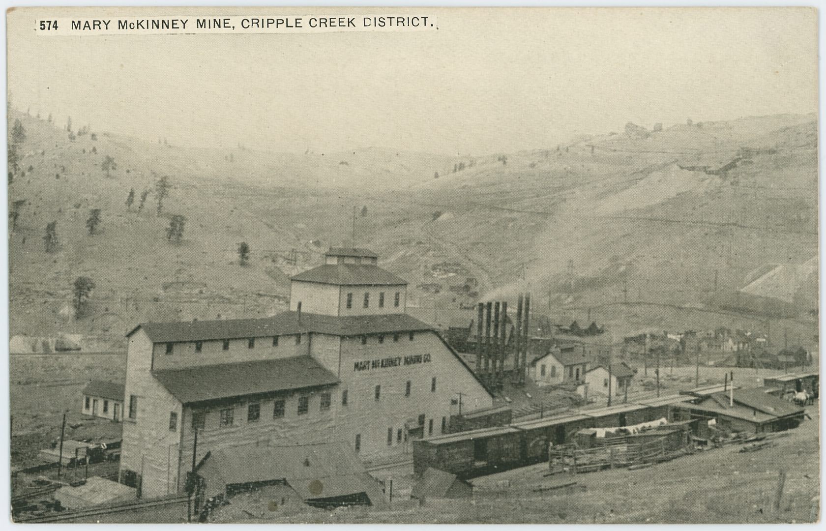 I've seen this image used three times, for this card and another postcard where there are a couple of extra millimeters visible on the right-hand side, plus I've seen it used in a postcard folder.
   The view is from the railroad side of the Mary McKinney mine, showing several box cars parked on sidings nearby and at the mine itself. It also shows part of Anaconda at right-hand side about 1/3 up from bottom, the part that survived the 1904 fire, as I see no signs of structures at left side of image, and I believe there should been visible something there if the town was still there.
   The tracks in the foreground belong to the Midland Terminal, but the Mary McKinney mine was once served by dual gauge as the F. & C.C was also having a spur to the mine, entering in from left-hand side, running parallel with the Shaft House to serve that and the coal bins at the power plant seen with all those smokestacks to the right of the shaft-house.
   Behind the smokestacks of the Power House of the Mary McKinney you can see the Ore House of the Anaconda Mine, located down by the F. & C.C. yard in Anaconda, but image is too bad to really make out any details. Which is sad, as up on Gold Hill seen in the background, there is seen the Shaft House of the Anchoria-Leland about 1/4 in from right-hand side and about same from top, with the Ore-House and trestle of the Lexington Mine seen just to the right of the Anchoria-Leland.
   Or even more sad, there is visible a mill on the hill side above the Low Line grade, seen about  1/3 down from top and 1/7 in from right-hand side, a mill I believe might be known as Anaconda Mill, but I might be mistaken where that mill was located as info been a little scarce, but it fit the location of west slope Gold Hill.
