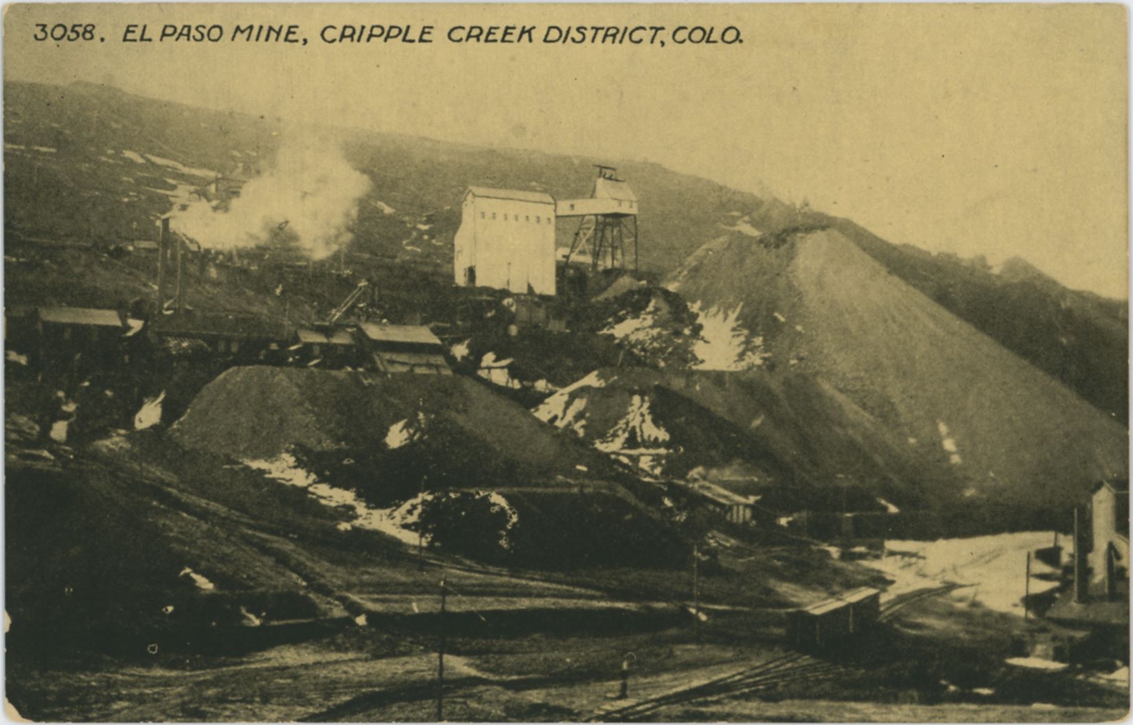 This image is a good one, in spite of the quality being too dark and that it sadly is of the printed type. But, the scene it shows makes it great as it shows the short-lived Switchback branch of the Florence & Cripple Creek that went down Beacon Hill to the Henry Adney & Old Gold mines in the valley below the impressive El Paso Mine, seen with its light colored large ore house and partly built in head frame about 1/3 from top at center of image.
   A little below that at left is the C.K. & N. Mine, seen about middle top/down and in lower right-hand corner is the Henry Adney mine with a couple of F. & C. C. boxcars standing on the track nearby.
   This image dates to a timeframe 1908-1917 due to the showing of part of a Orehouse in lower right that was built at Henry Adney around January 1908, till the branch line was abandoned sometime in 1917.